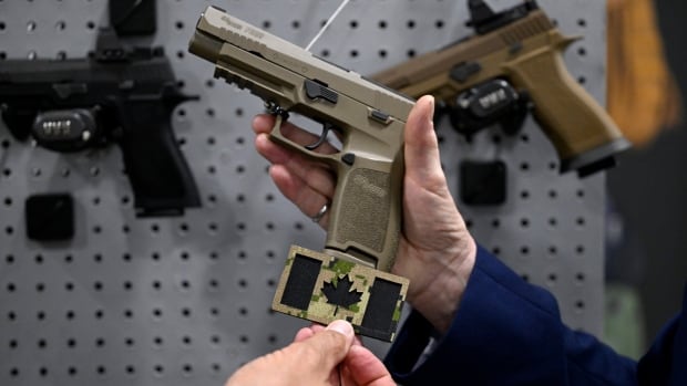 A handgun with a Canadian maple leaf patch shown beside it.