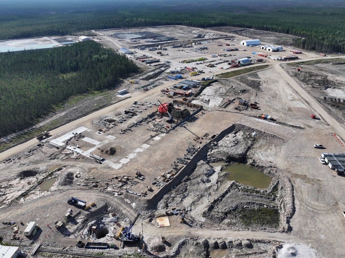 An overhead view of a mine site, lots of dirt, surrounded by forest.
