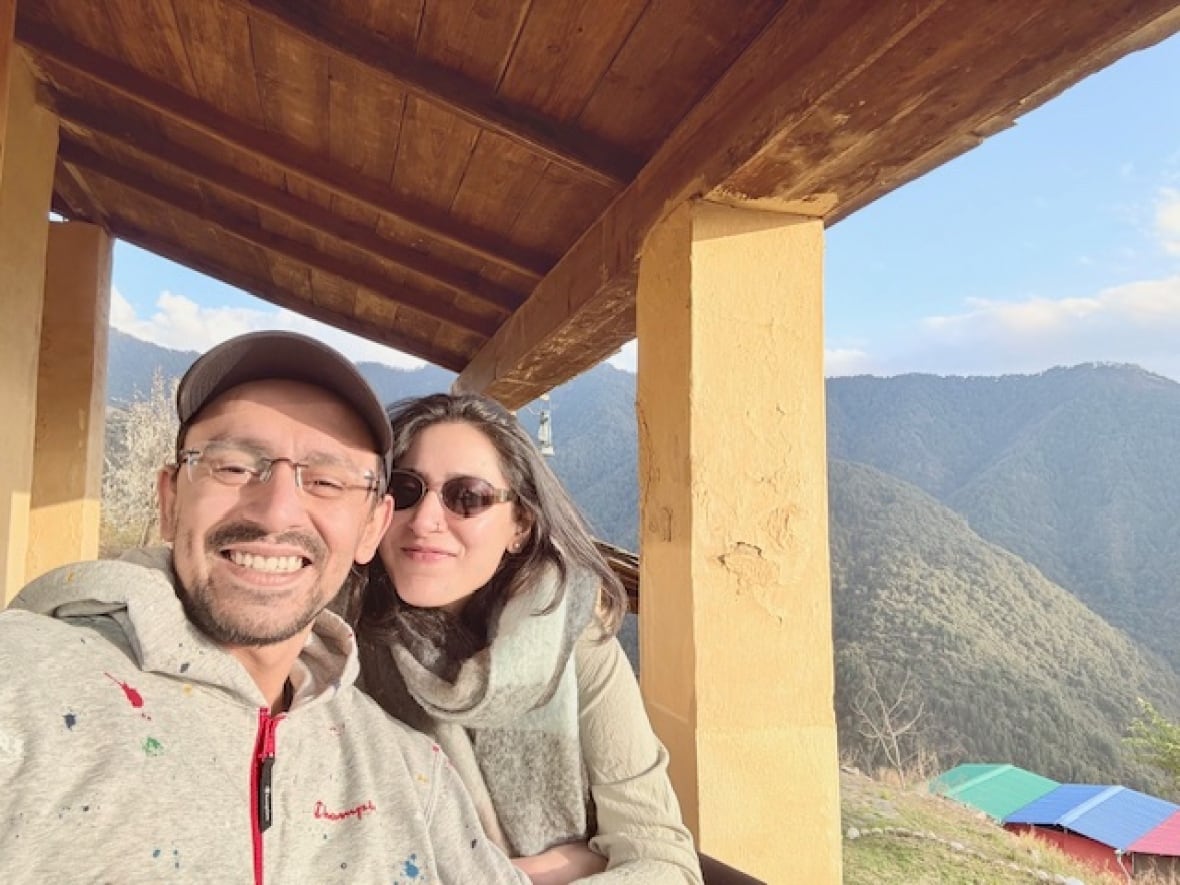 A man and a woman pose together for an outdoor photograph in a mountainous area.
