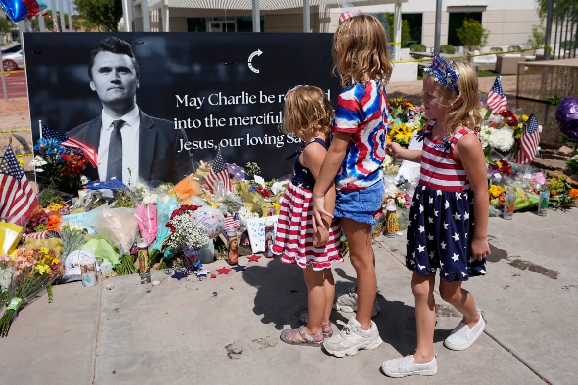 Three children stand at a memorial