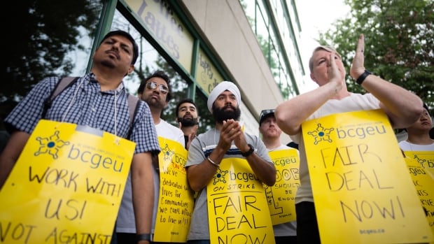 A group of striking workers holding yellow signs demanding fair wages during a rally.