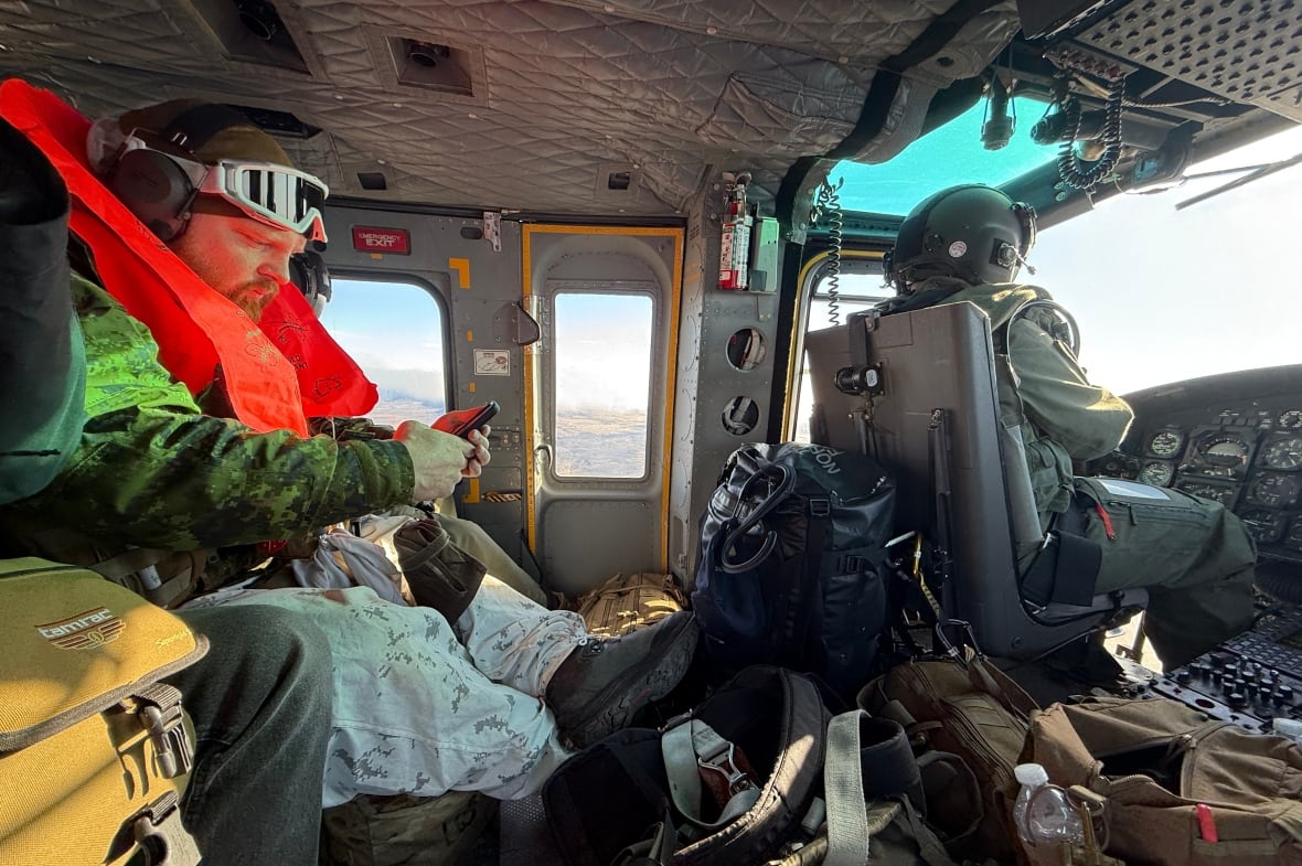 A soldier and pilot sitting in the narrow interior of the military helicopter. 