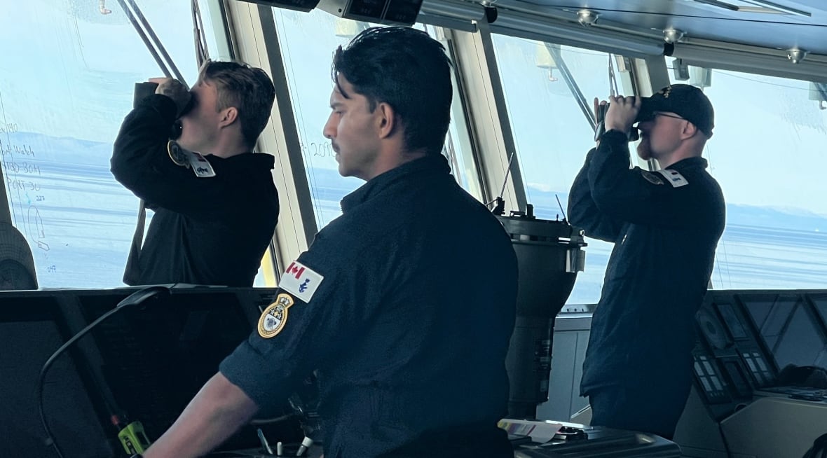Three sailors stand on a marine ship bridge - one guidance while others look through perspectives. 