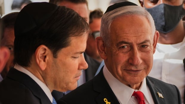 Two men speak surrounded by a crowd.