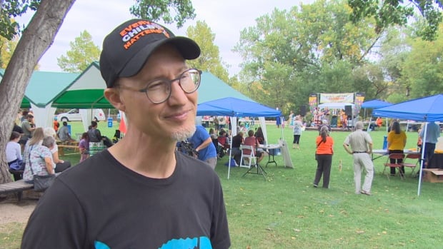 A man in a black hat and t-shirt with glasses