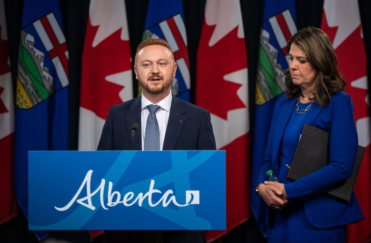 A man and a woman stand near a podium.