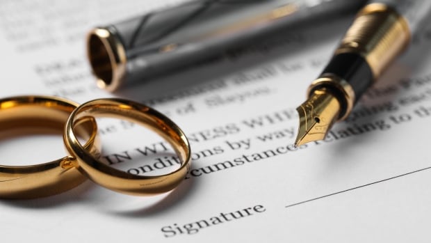 Fountain pens and two gold rings atop a printed contract 