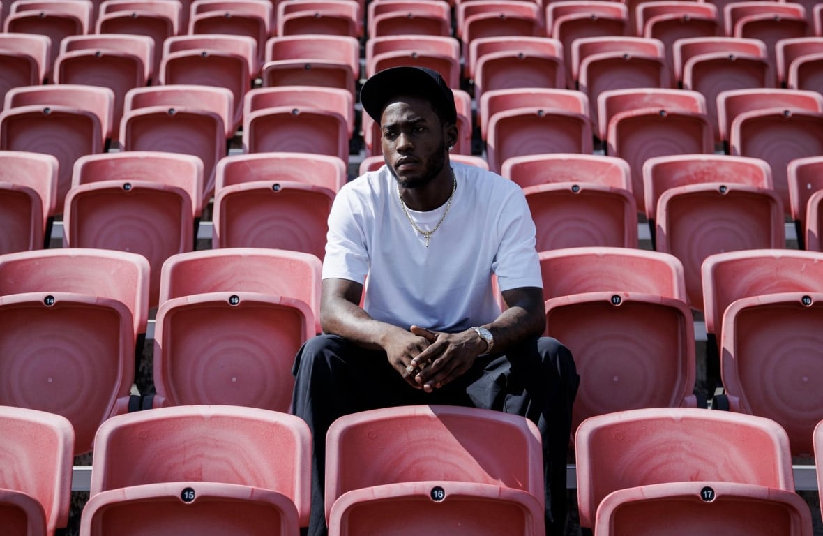 Man sits on red chair in field