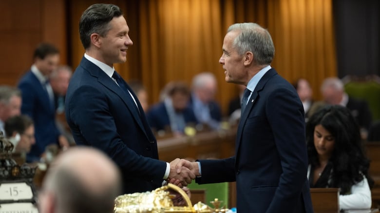 Two men in suits shake hands in a legislative hall.