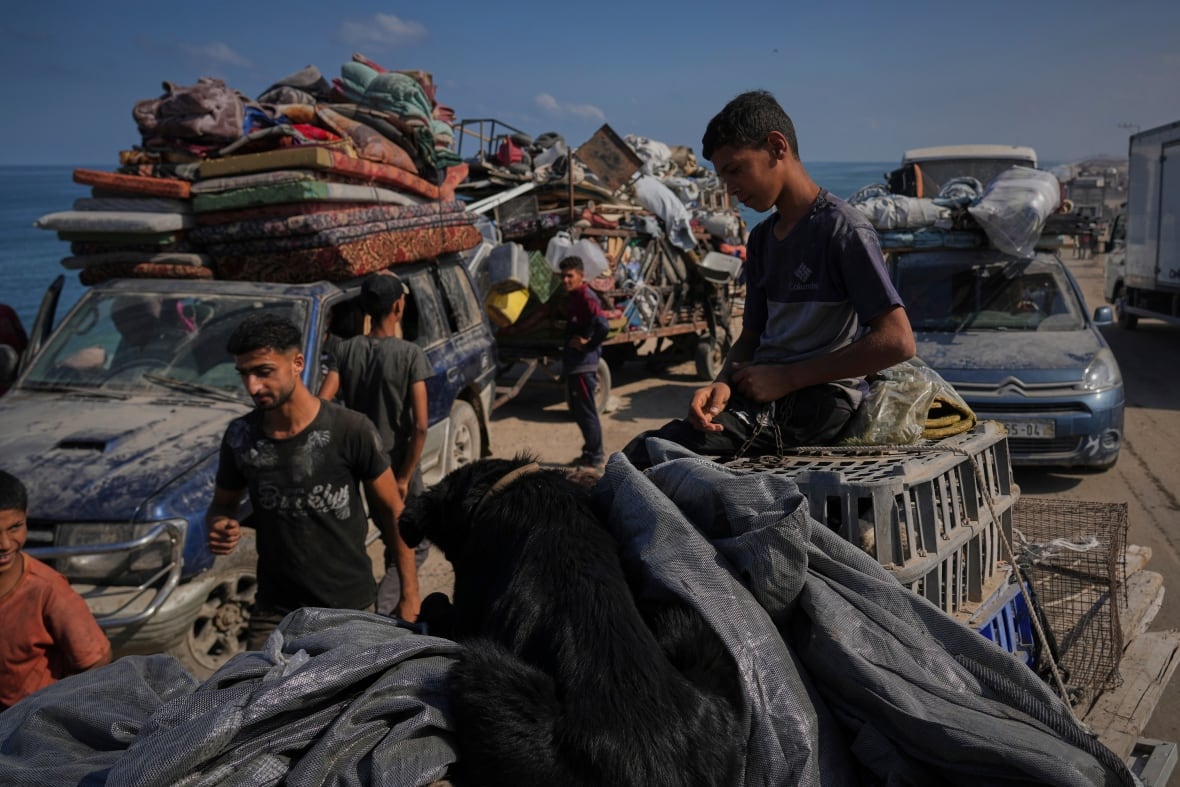 Men and children stand near the crowded cars that escape violence.