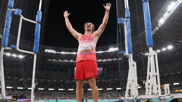A men's hammer thrower throws his arms up in celebration.