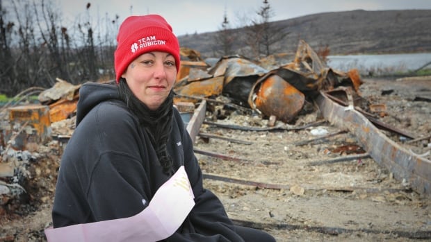 A woman wearing a red hat sitting in front of metal and rubble.