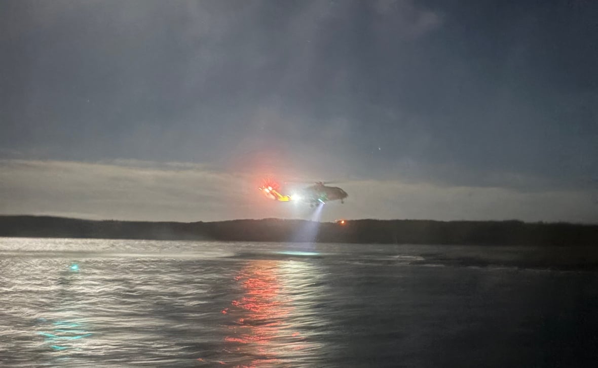 A helicopter hovering above the ocean at night.