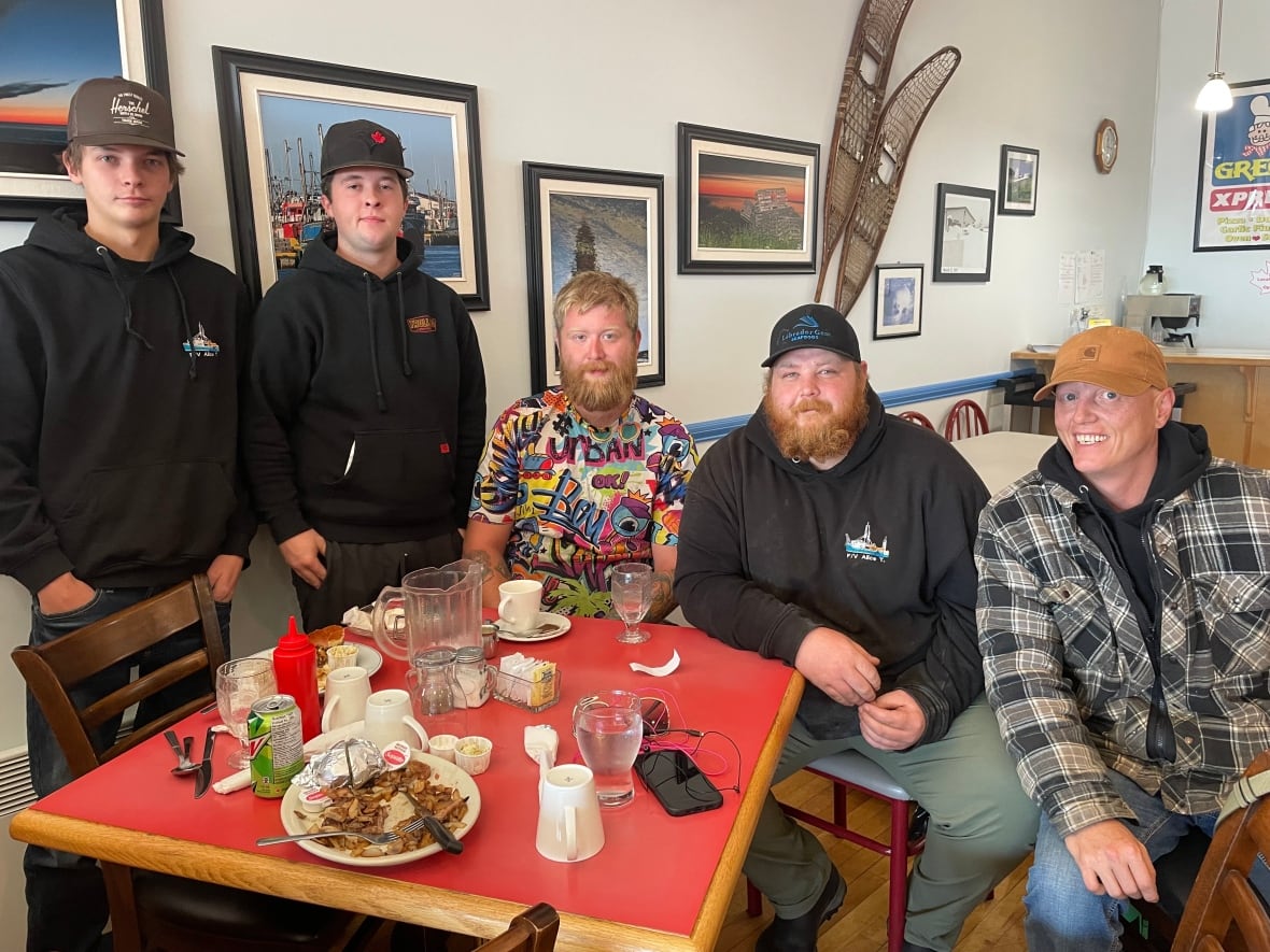 Five men sit around a red table.