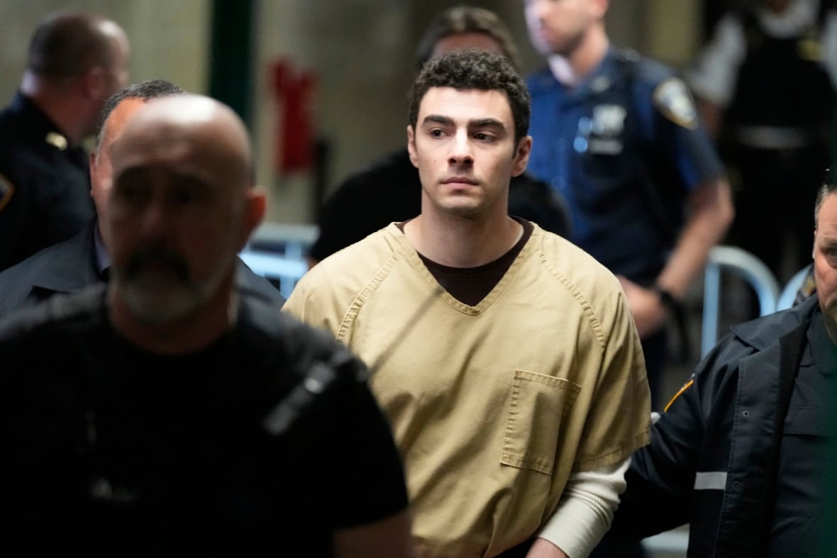 A man in focus, surrounded by officers. 