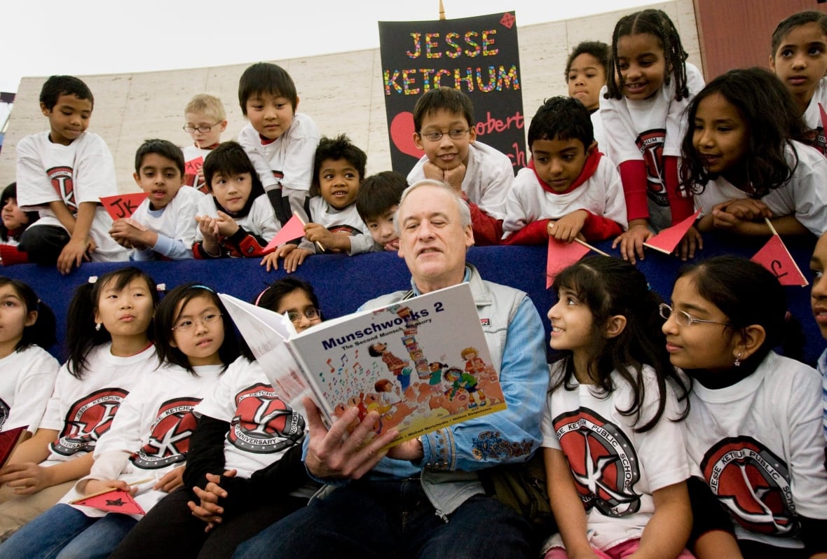 An older man reads a book to a group of children
