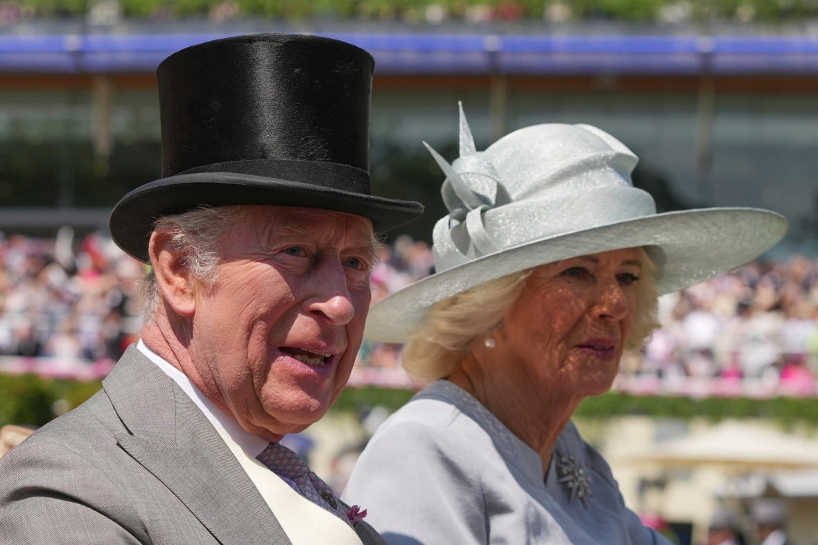 King Charles and Queen Camilla in an open vehicle on a summer day