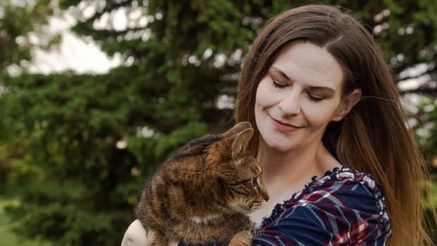 Woman in plaid shirt holds a cat