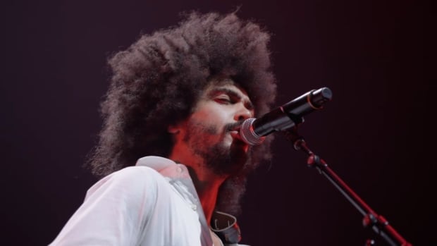 Yves Jarvis plays guitar while wearing a white shirt.
