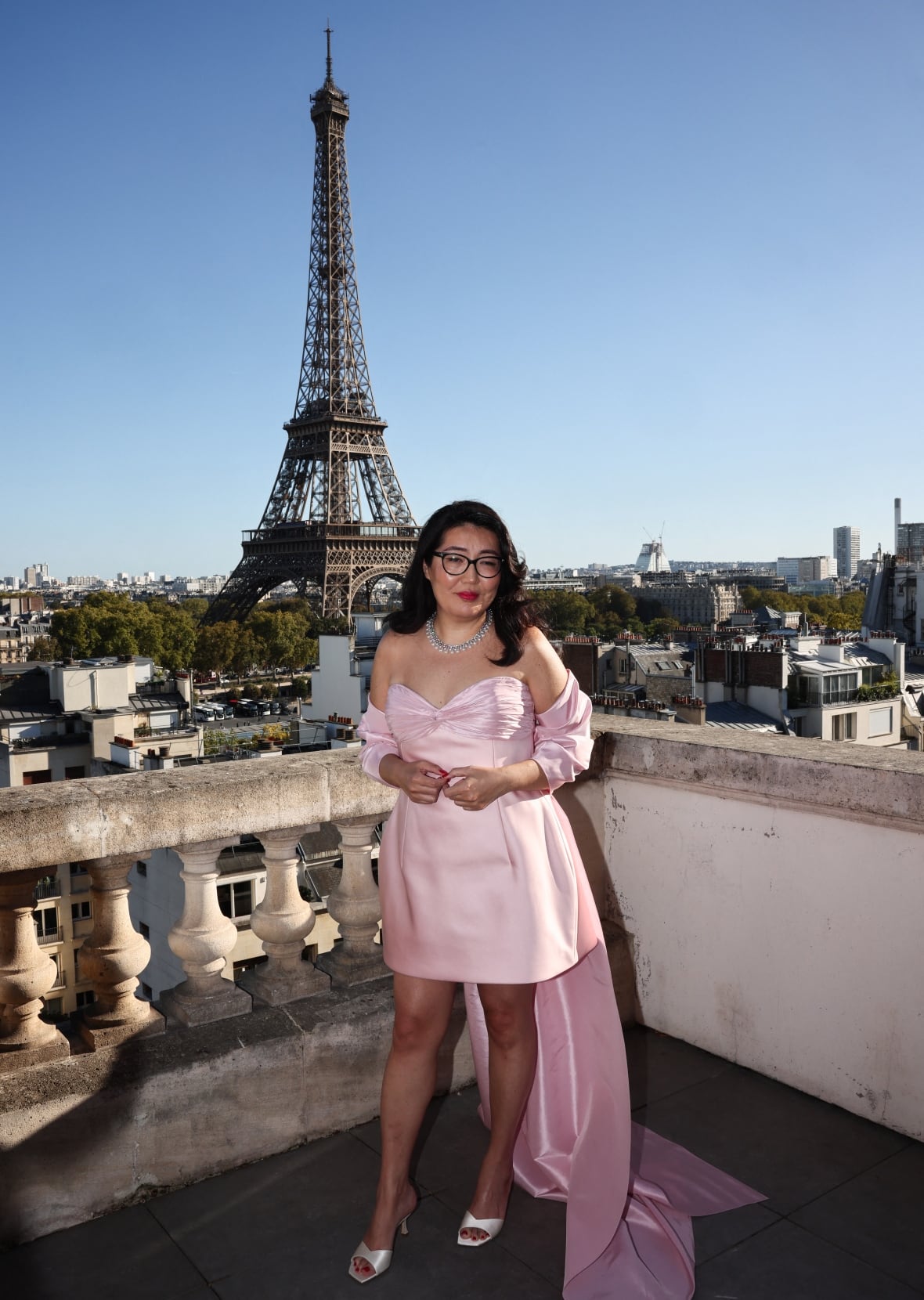 a woman in a pink dress stands on a rooftop with the eiffel tower in the background
