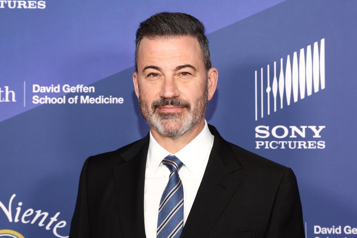 A medium shot of a man in a suit, smiling for the camera. 