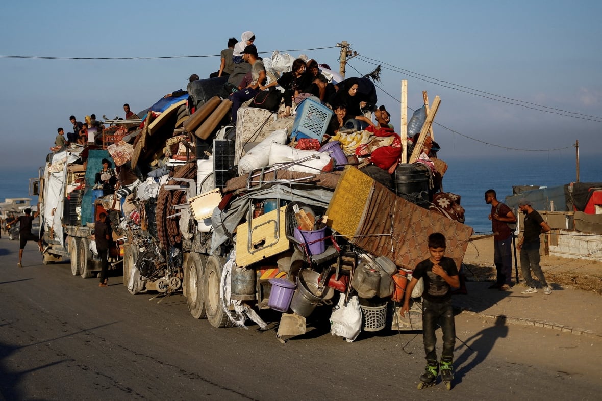 People sit on top of a truck with stacked property.