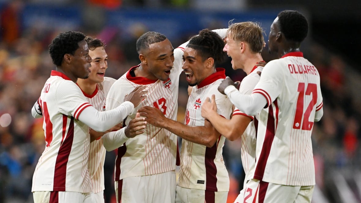 Soccer players representing Canada celebrate after scoring a goal.