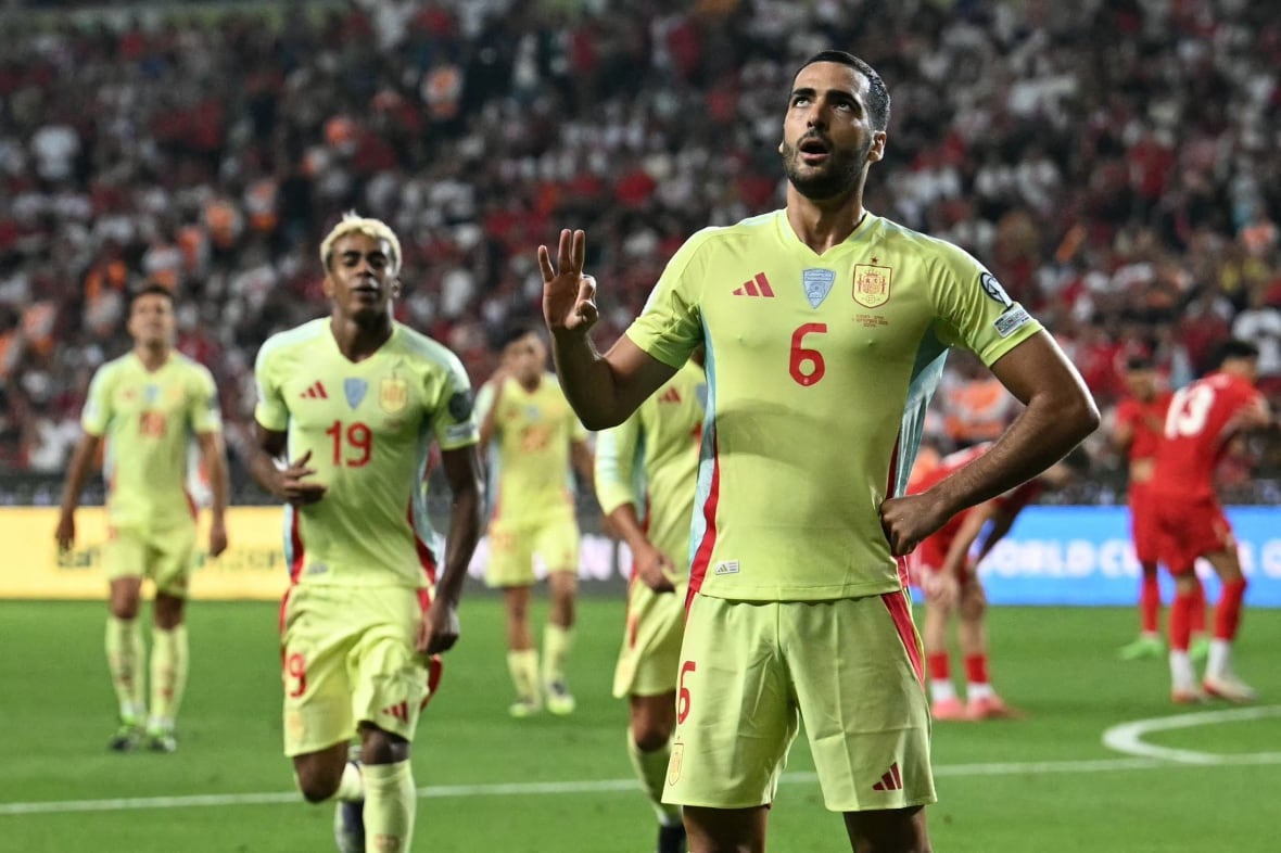 A soccer player representing Spain celebrates a goal by holding up three fingers.