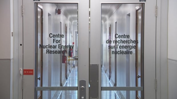 Double metal doors, each with a large window, with a hallway on the other side. The words "Centre for Nuclear Energy" research in black letters on one door.