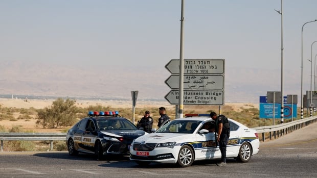 Police officers stand next to their cars at a crossing.