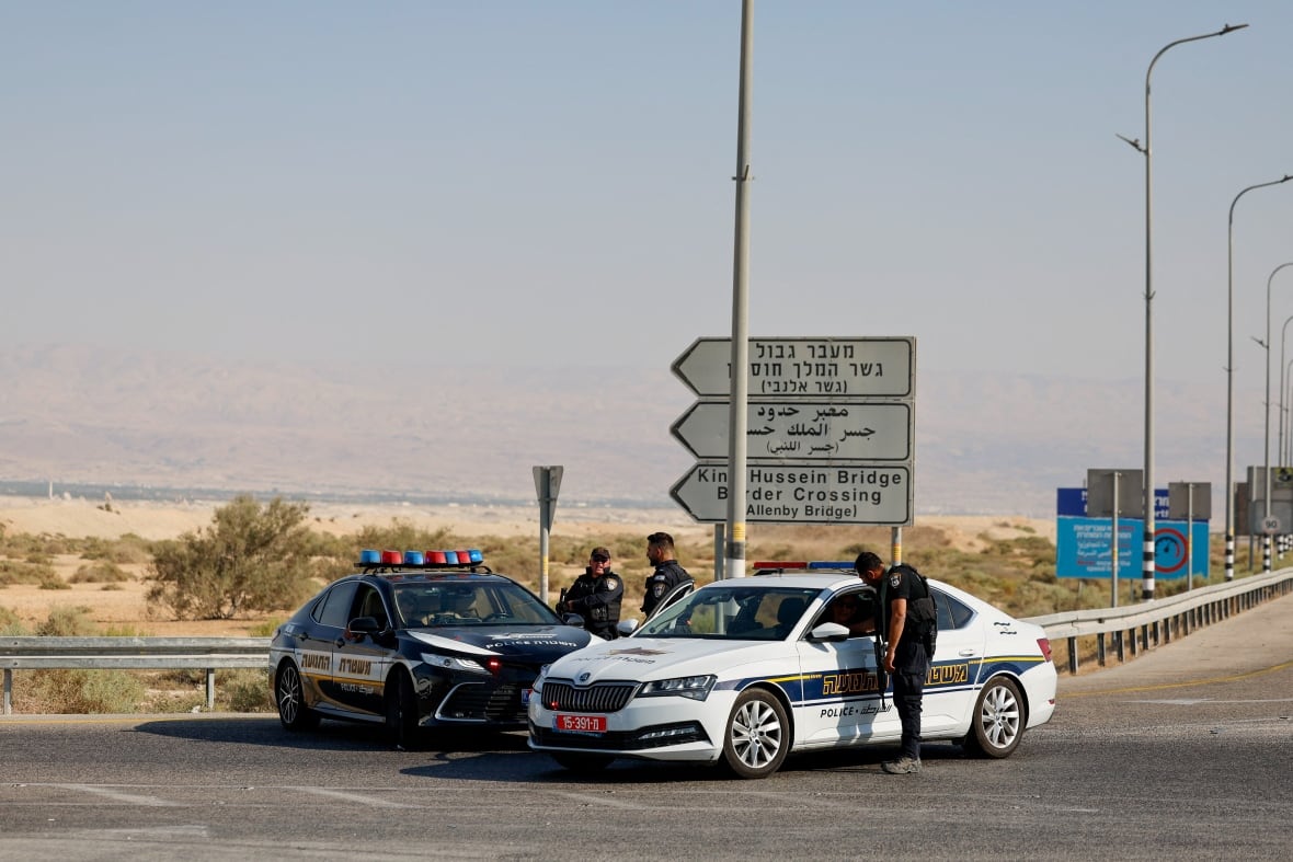 Police officers stand next to their cars at a crossing.