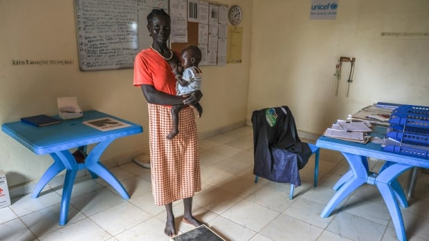 A woman holds a baby in a hospital room.