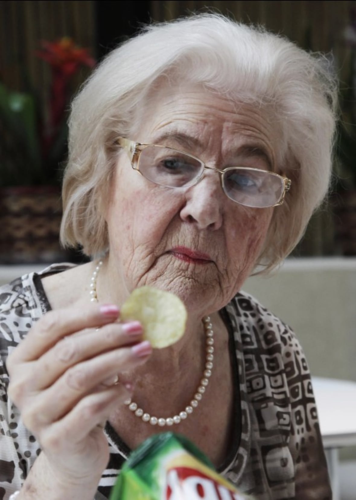 Woman named Marilyn Hagerty holding up a chip while holding a bag of lays.