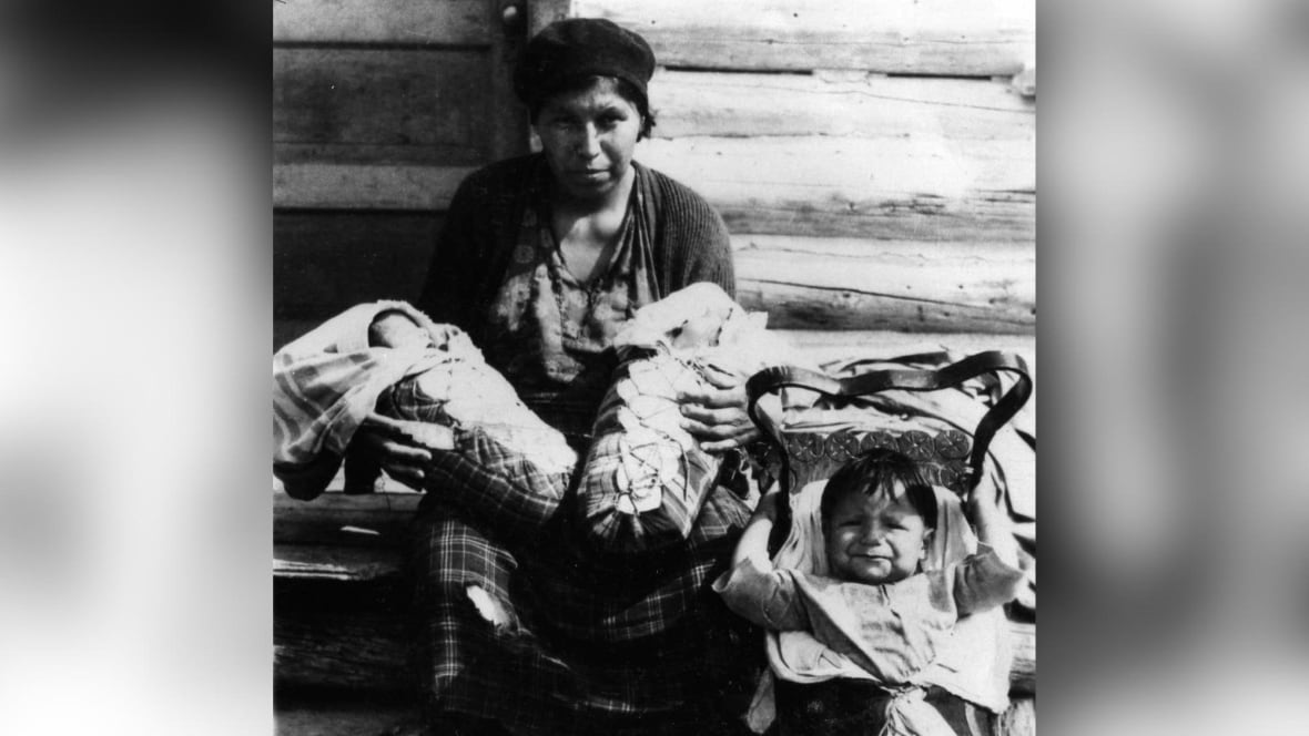 An old black and white photo of a mother with two babies and a toddler.