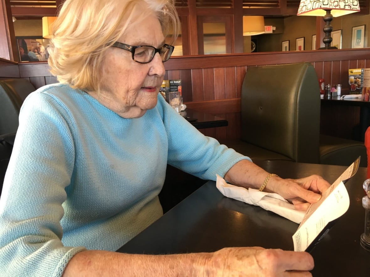 A woman named Marilyn Hagerty holds a paper while sitting at a table.