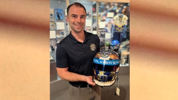 smiling man holds helmet