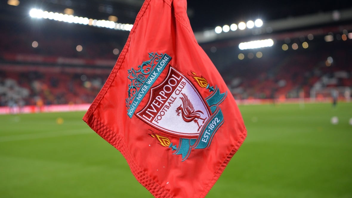 A flag bearing the Liverpool FC logo sits on a corner pole on a soccer pitch.
