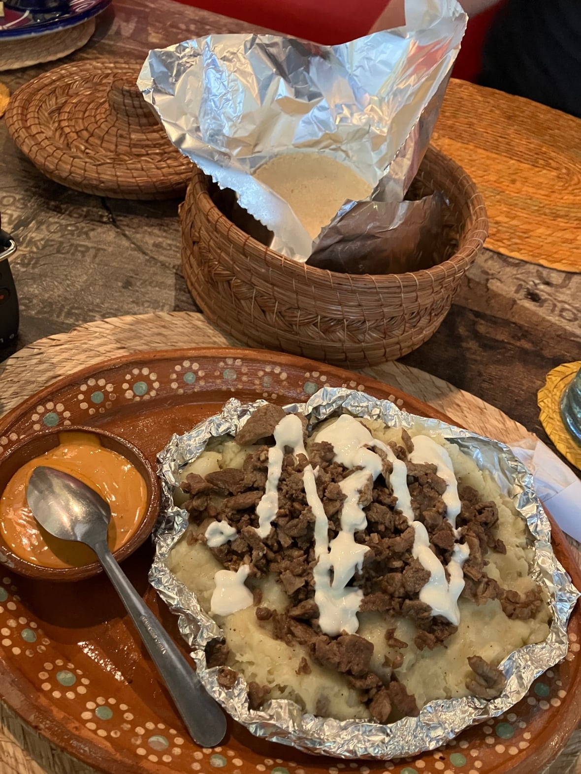 Mashed potatoes and meat on a plate beside some sauce.