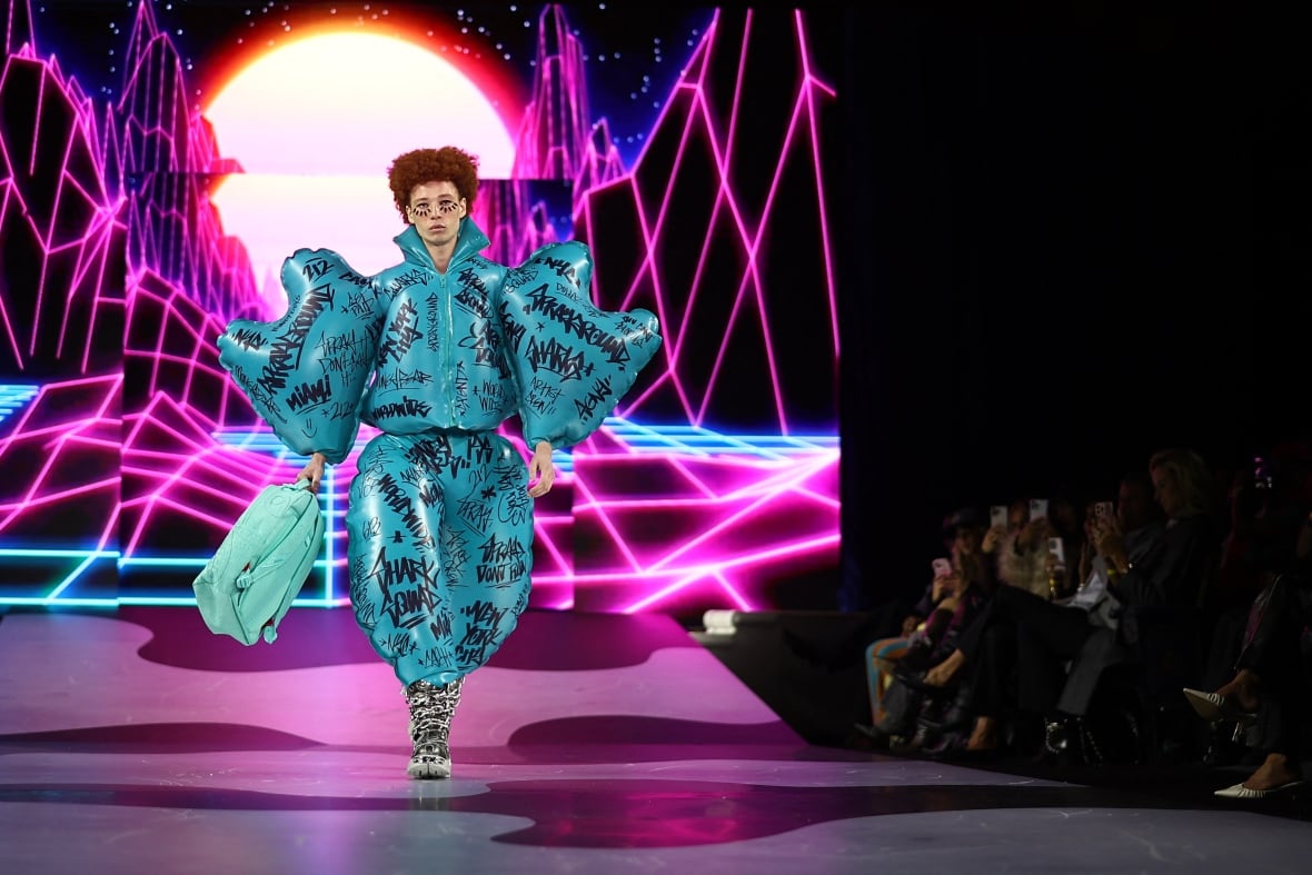 The model is walking around runway, when a turboise dress looks at a burning balloon of skills.  