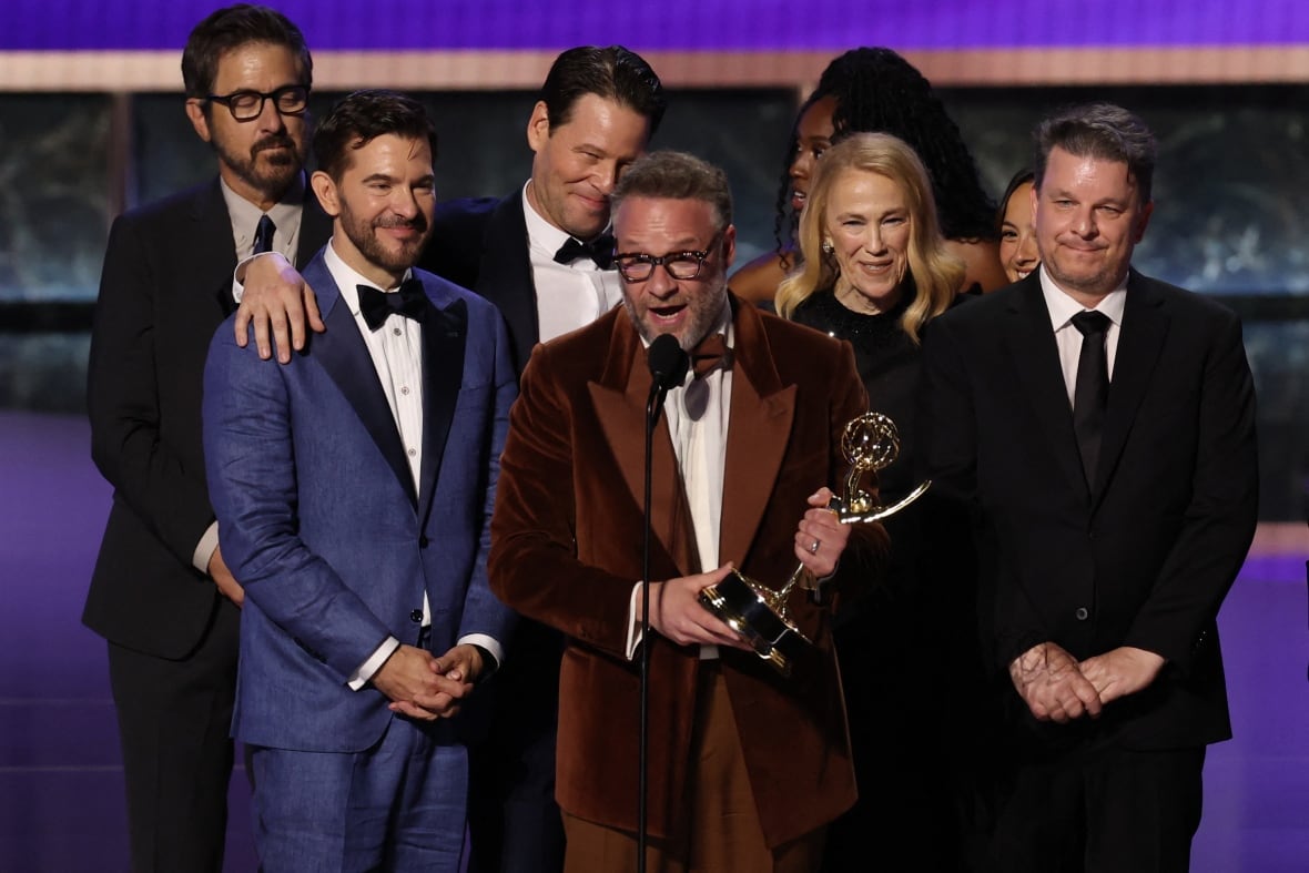 A beard man has grabbed the Emmy Award and others behind him on the stage to make a reception talk.