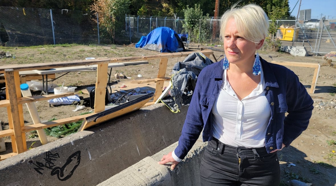 Une femme se tient dans un camp de sans-abri.