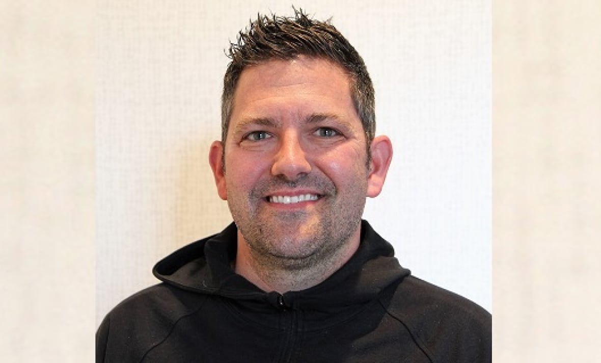 A smiling man with short spikey hair and a black hoodie.