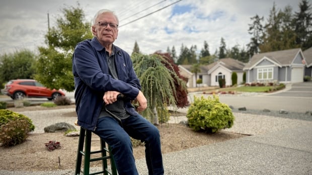 A man sits on a chair in his driveway.