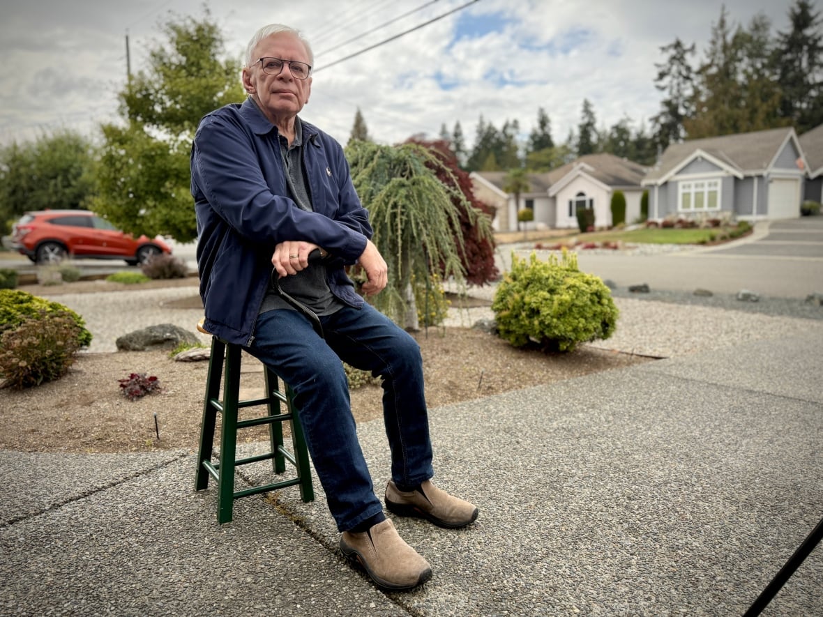 A man sits on a chair in his driveway.