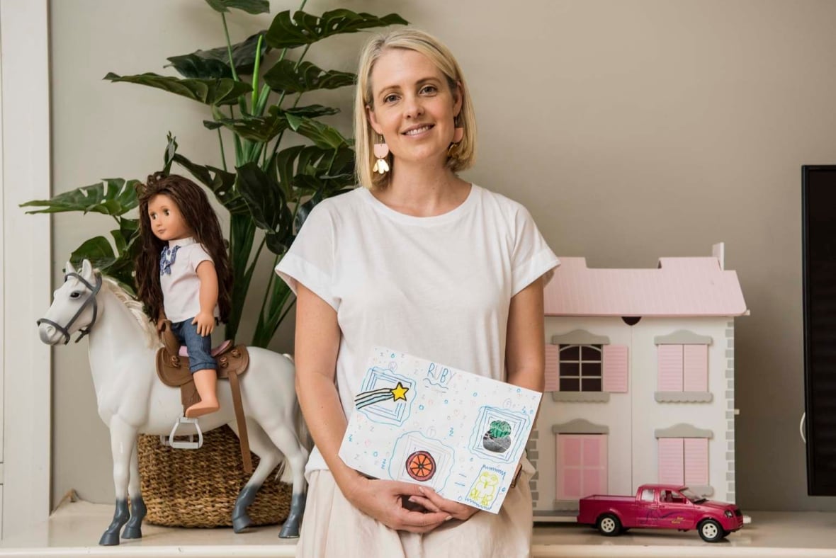 A woman stands in front of a wall decorated with children's letter.