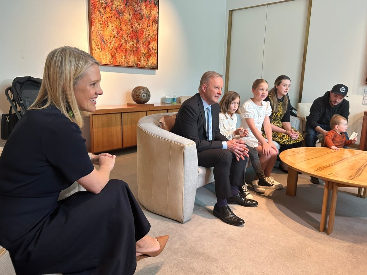 A woman, a man and children sit on the sofa together.
