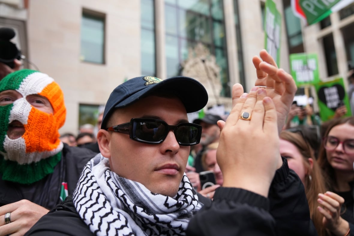 A man applauds, surrounded by a crowd.