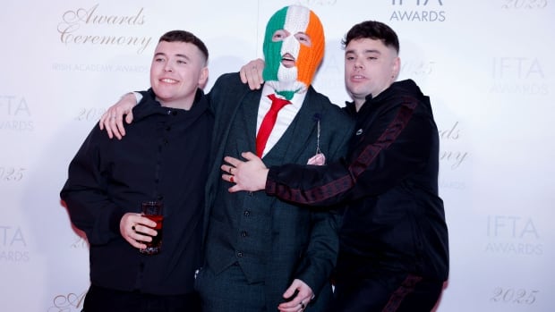 Three men playfully pose for a photo.