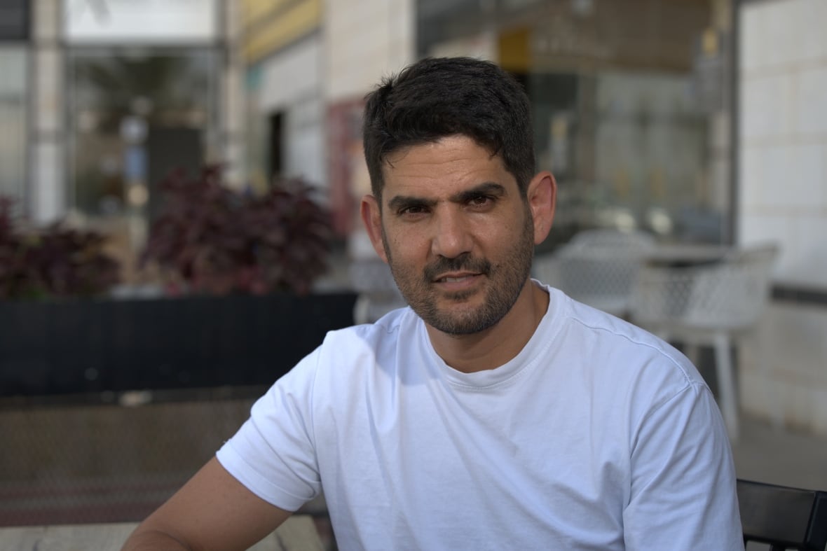 A man in a white T -shirt sitting abroad.