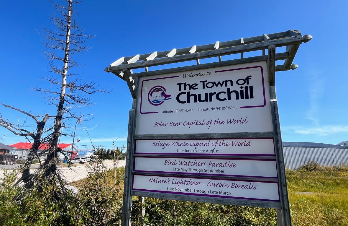 Uma placa é lida "Churchill, Manitoba," e tem slogans, incluindo "Polar Bear Capital do mundo" e "Beluga Whale Capital do mundo."